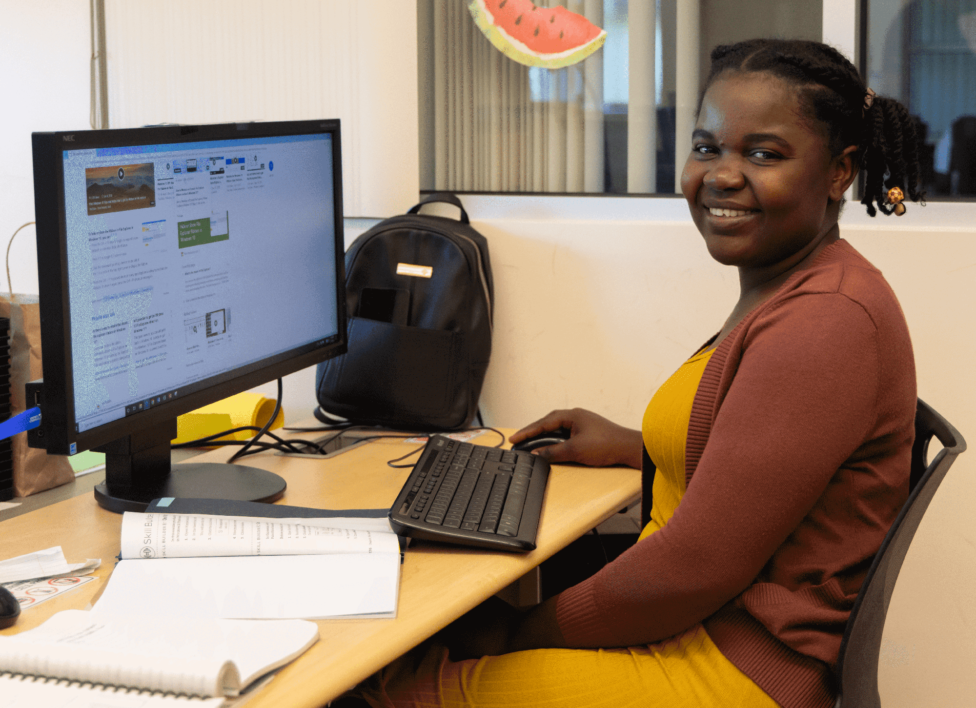 A woman sits at a desk with a computer