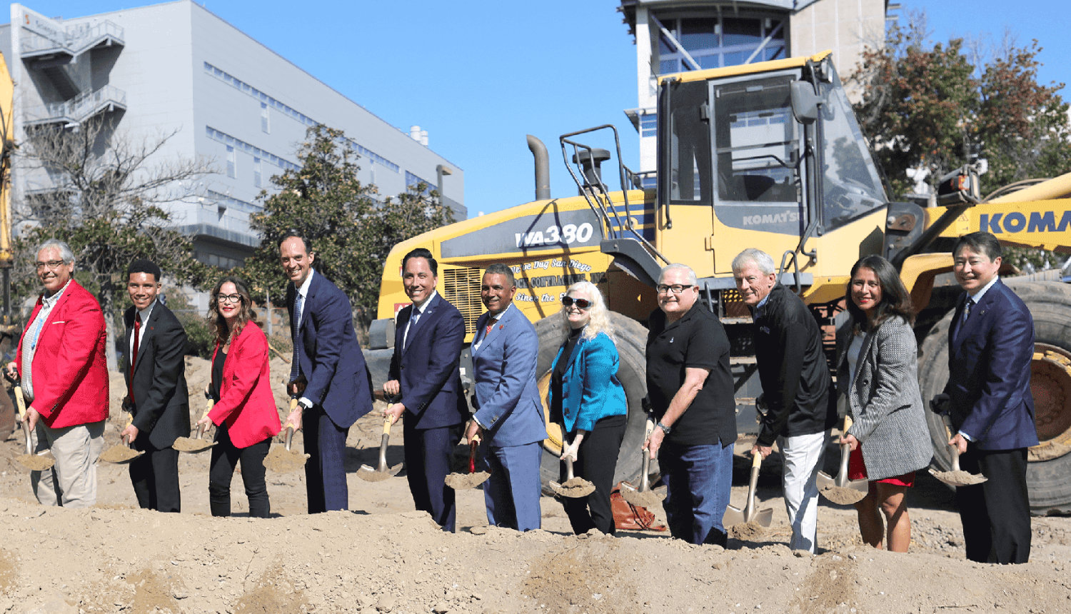 Eleven district leaders shovel dirt at a groundbreaking ceremony.