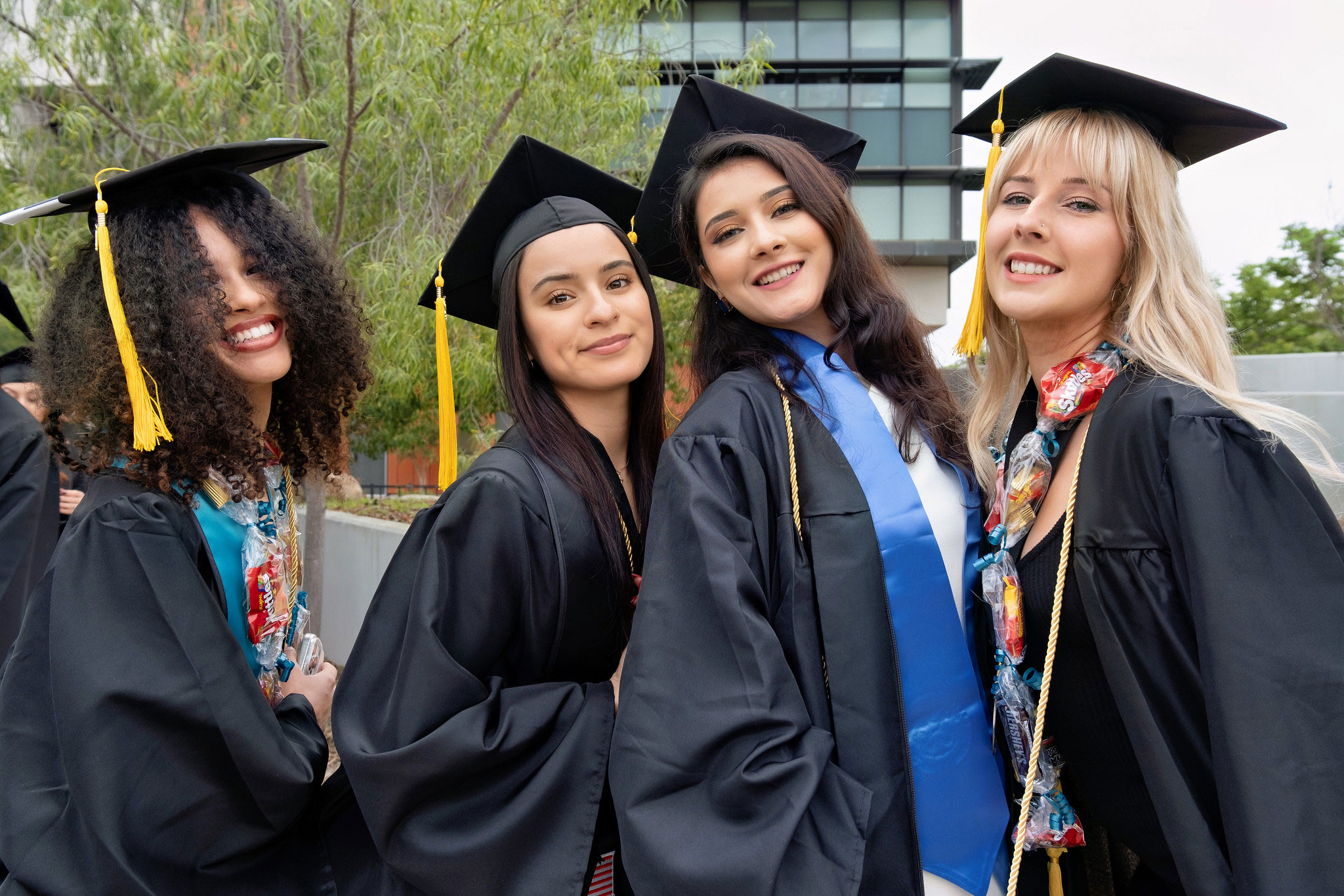 Four women in black graduation caps and gowns at commencement
