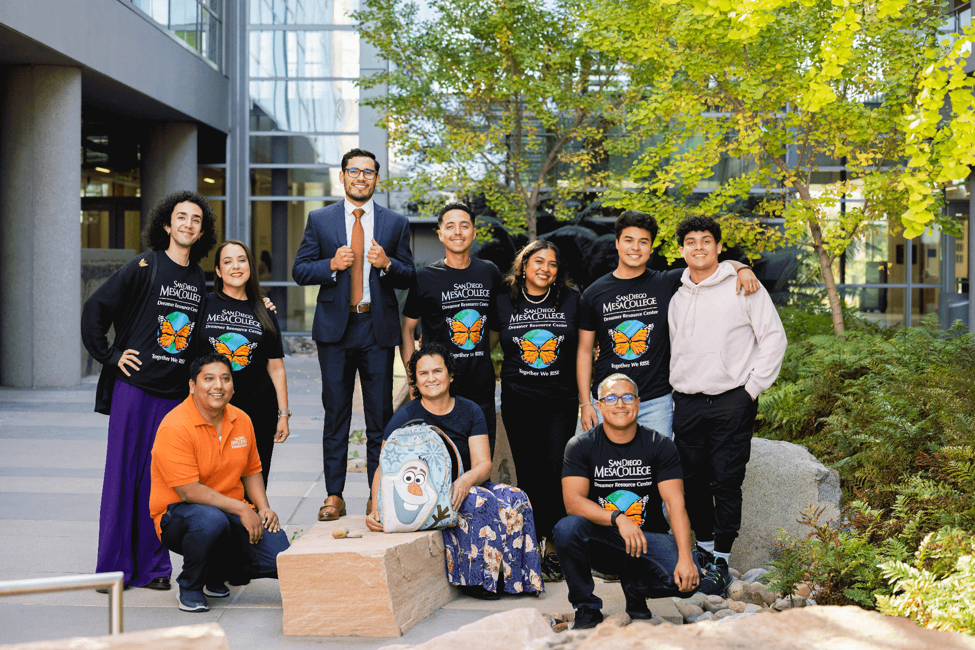 10 people outside in a courtyard. Six are wearing black t-shirts with a butterfly on them in support of undocumented students.
