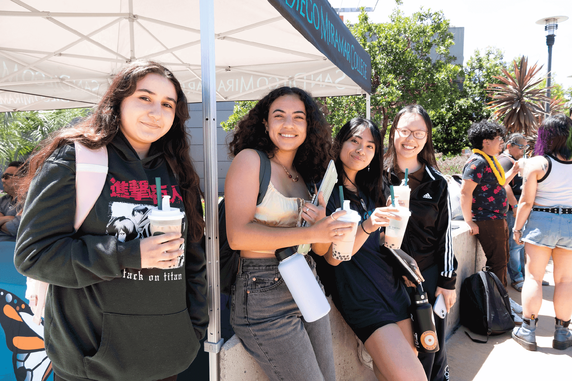 Four students drink boba under a canopy during welcome week