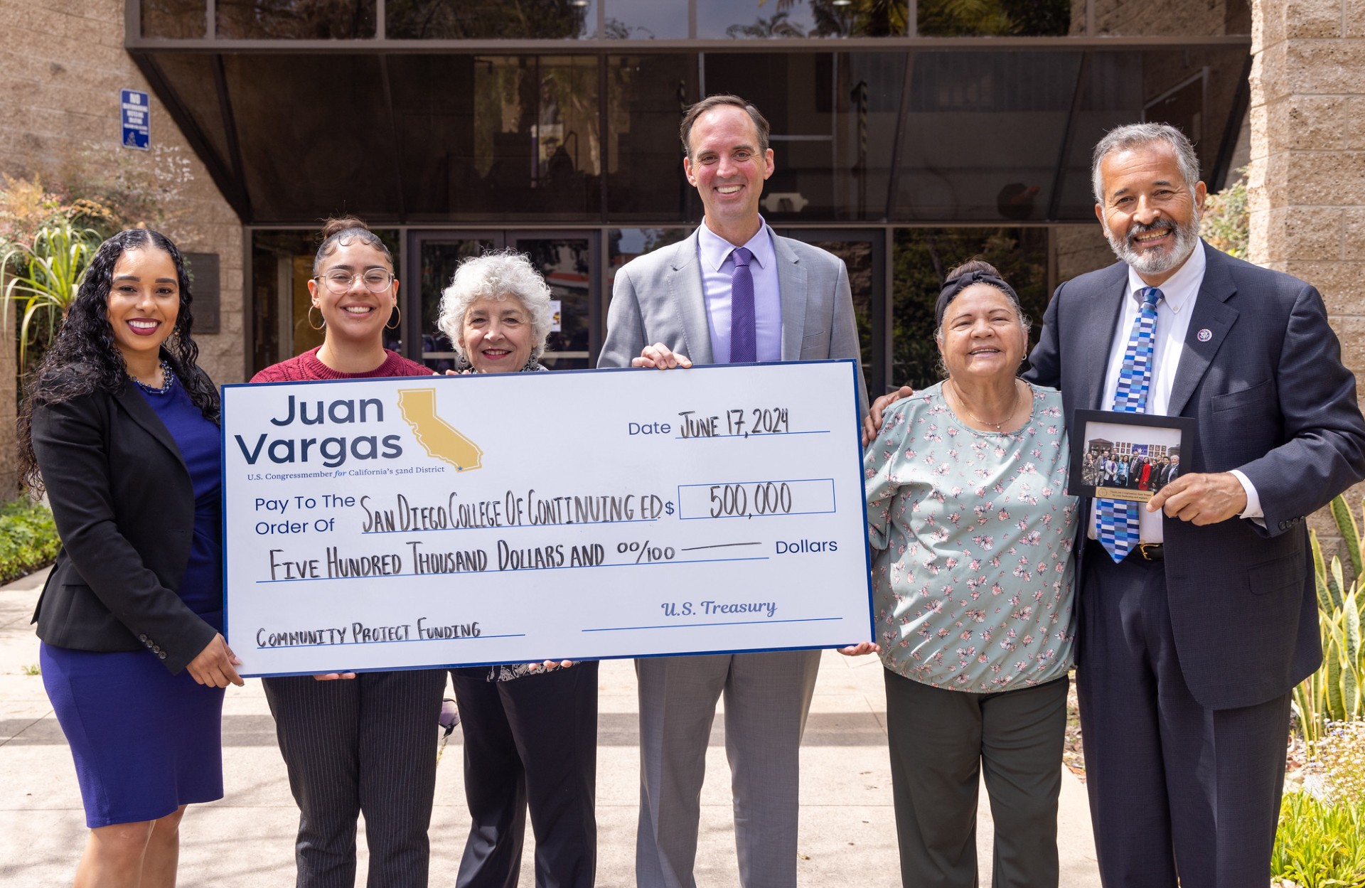 Six people hold up a giant check for 500,000 dollars