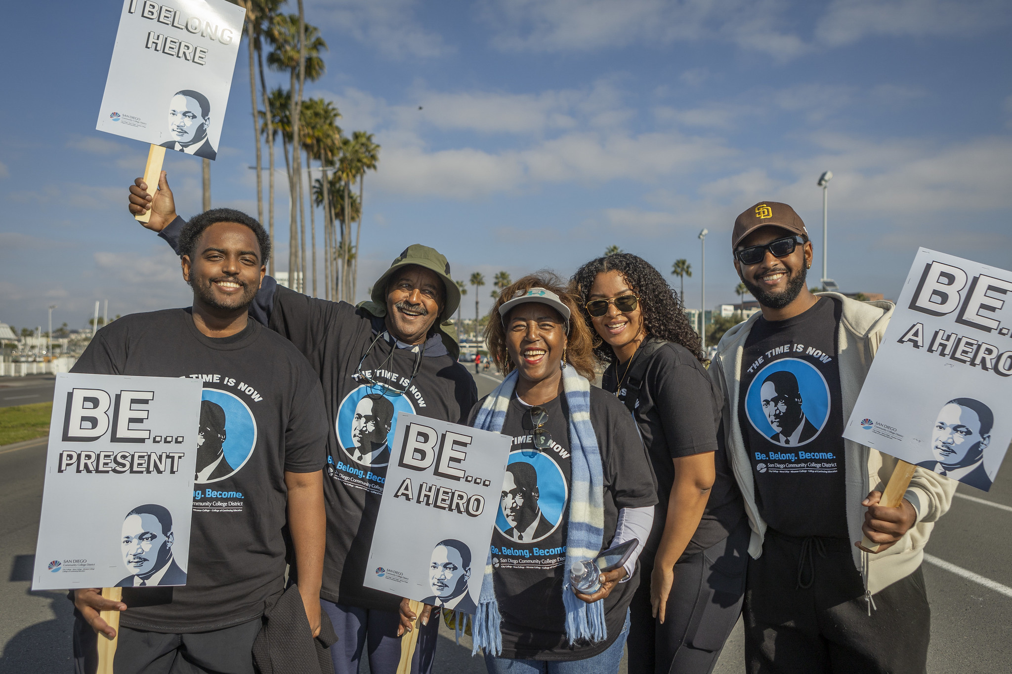 Five district employees walking in the Martin Luther King Jr. Parade hold signs that say be a hero.