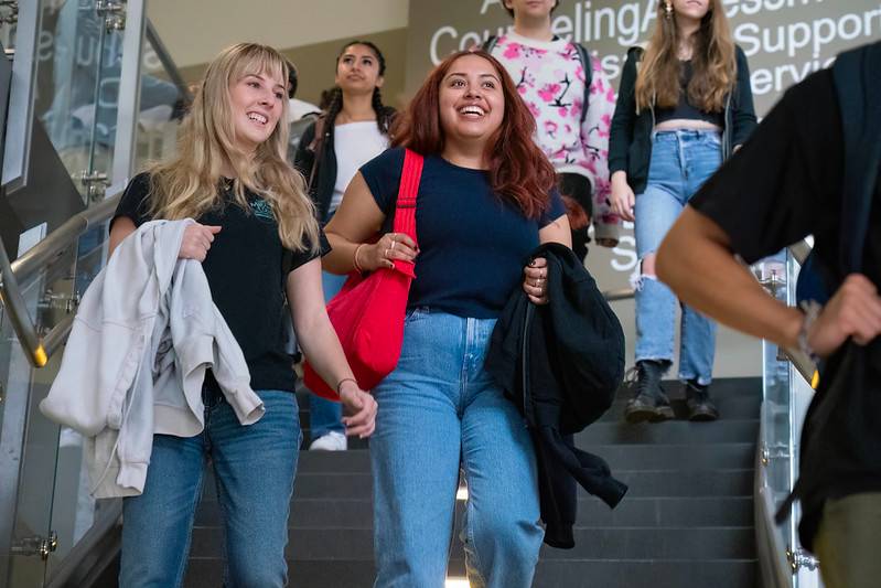 Five students walking down stairs in a campus building