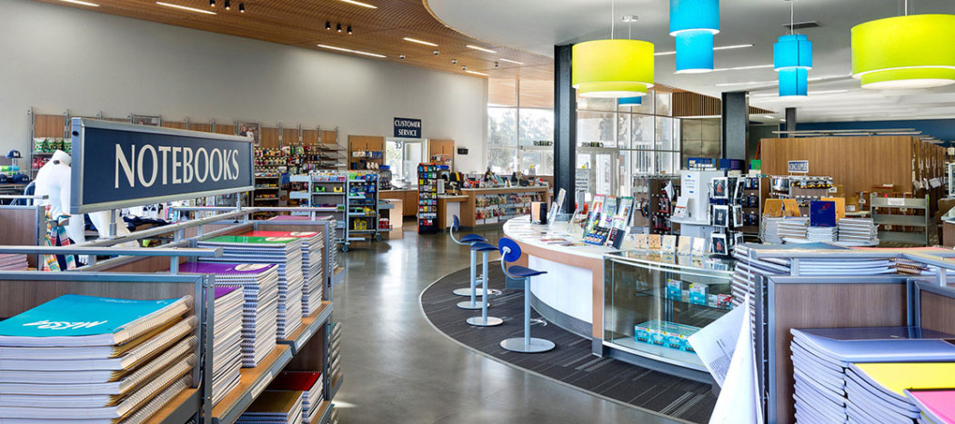 The Miramar College bookstore has multiple bookshelves and college merchandise on display.