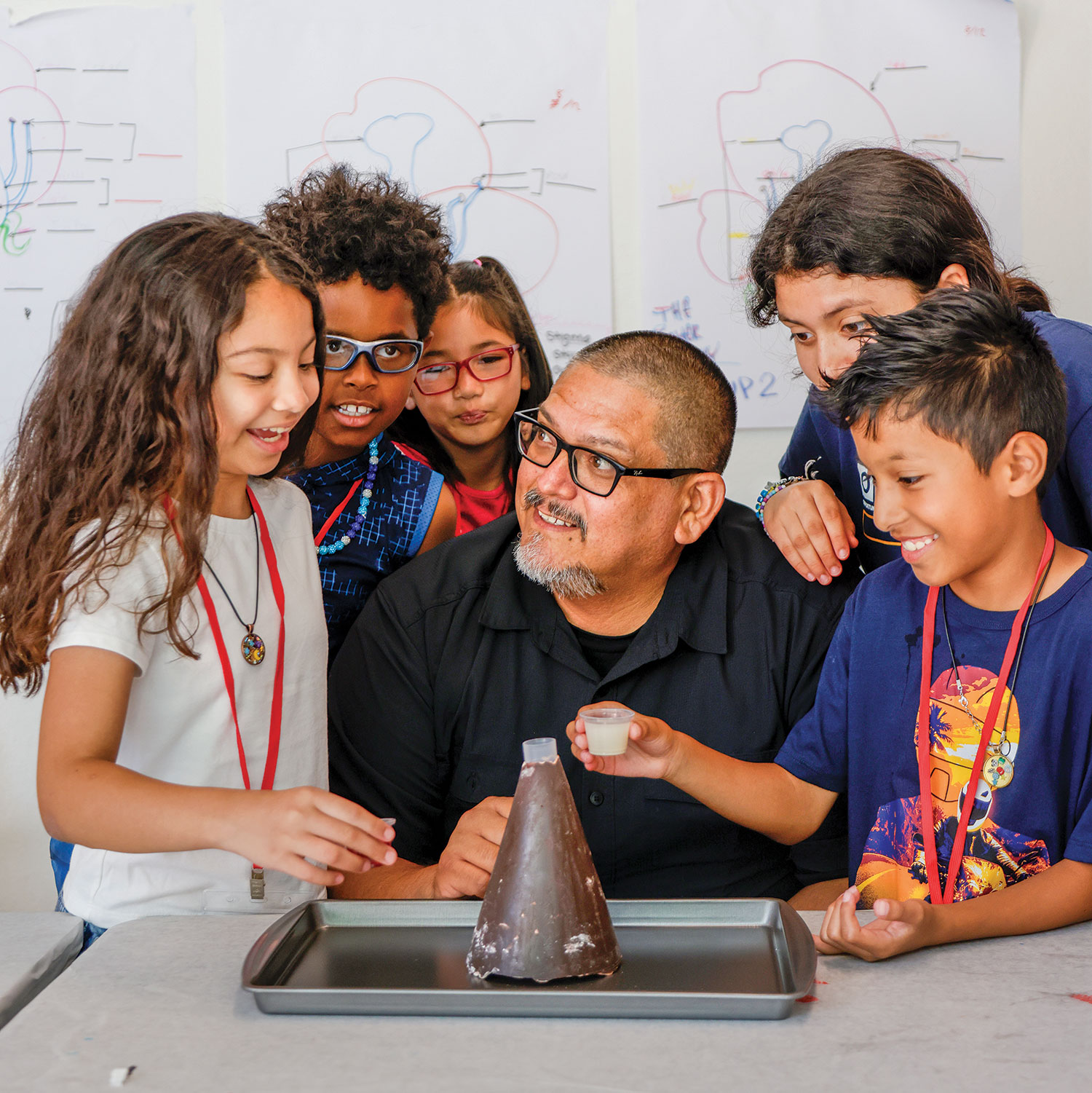 Beto Vasquez and five kids in a classroom work on a volcano.