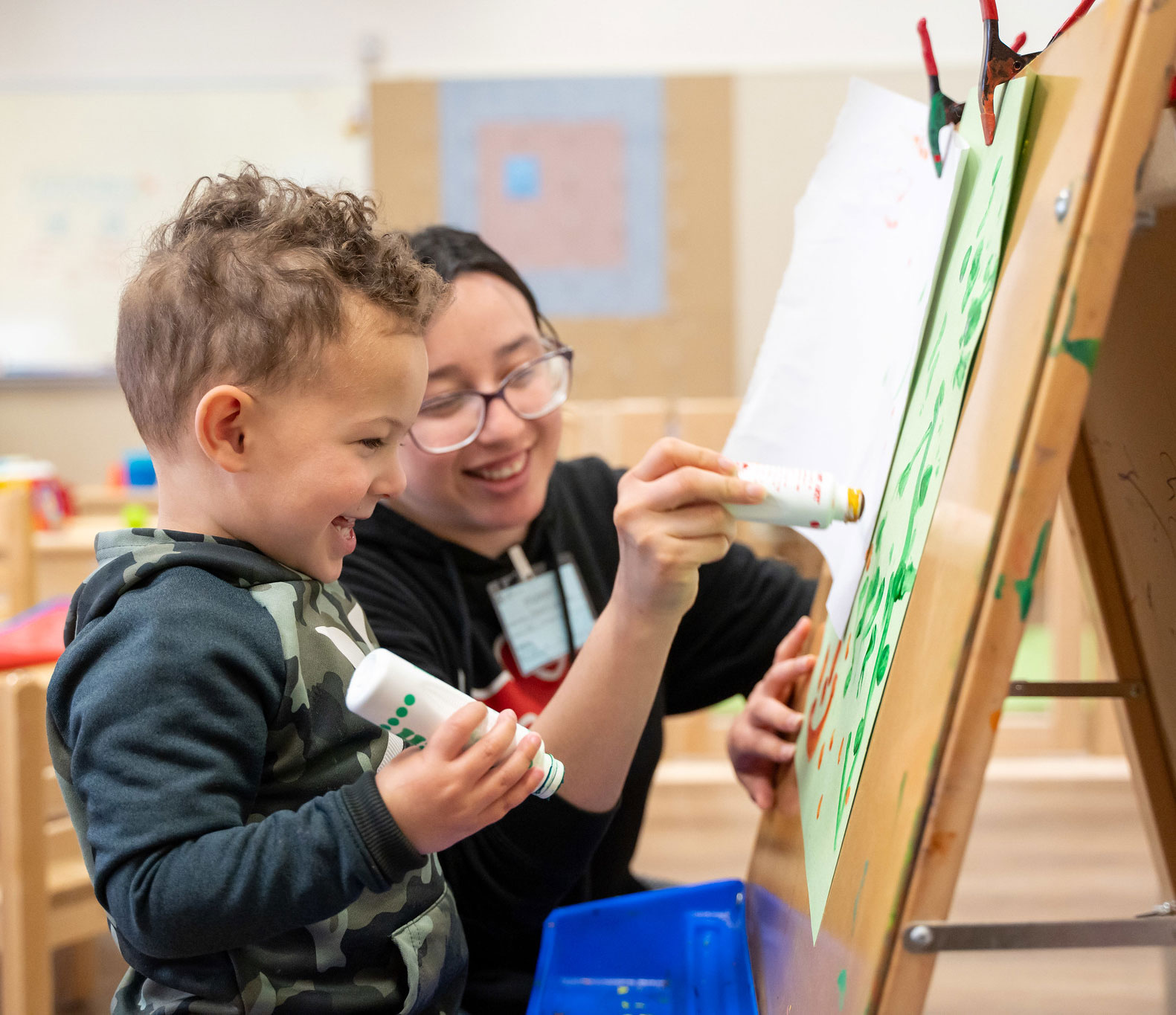 A student draws on an eisel with a small boy