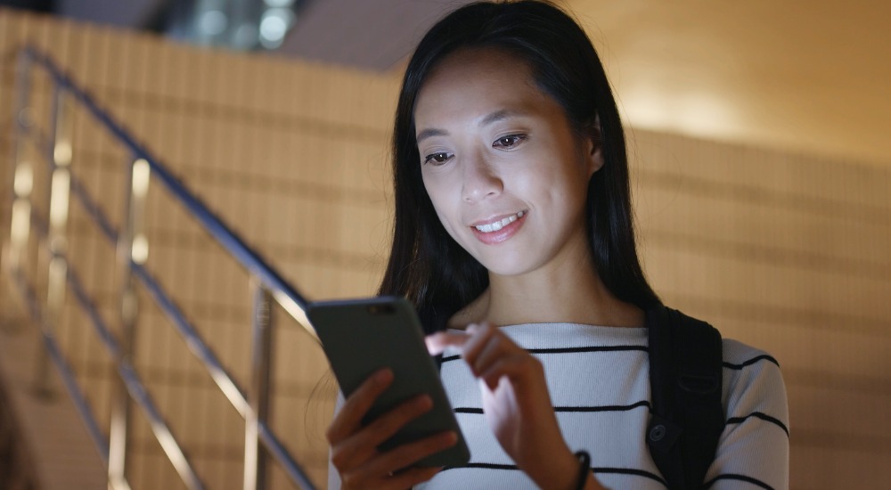A woman taps the screen of her cell phone.