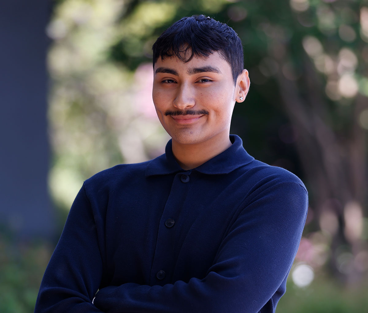 Jesse Lopez in a navy blue shirt outside surrounded by greenery