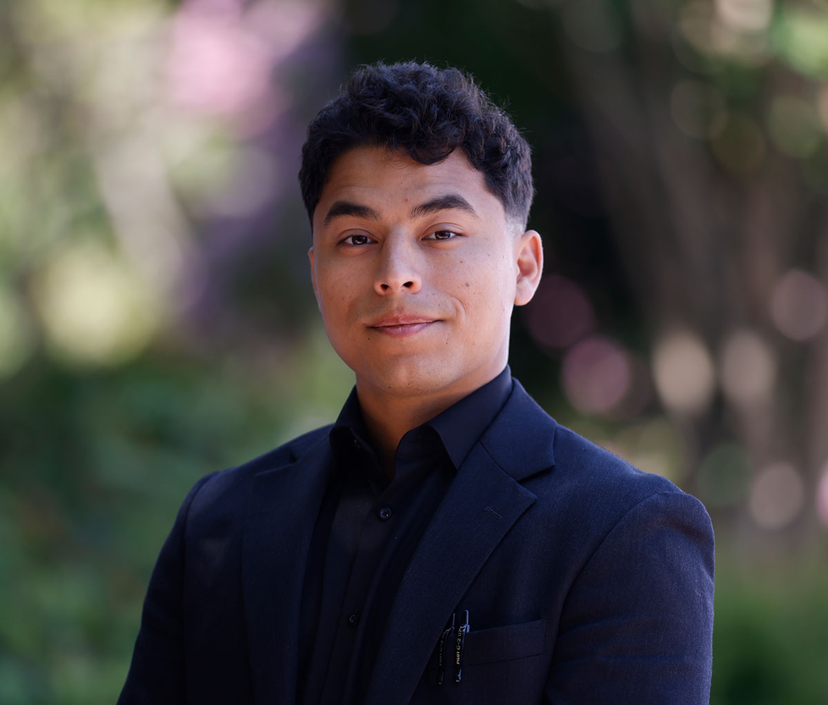 Michael Fuzy in a navy blue blazer outside surrounded by greenery