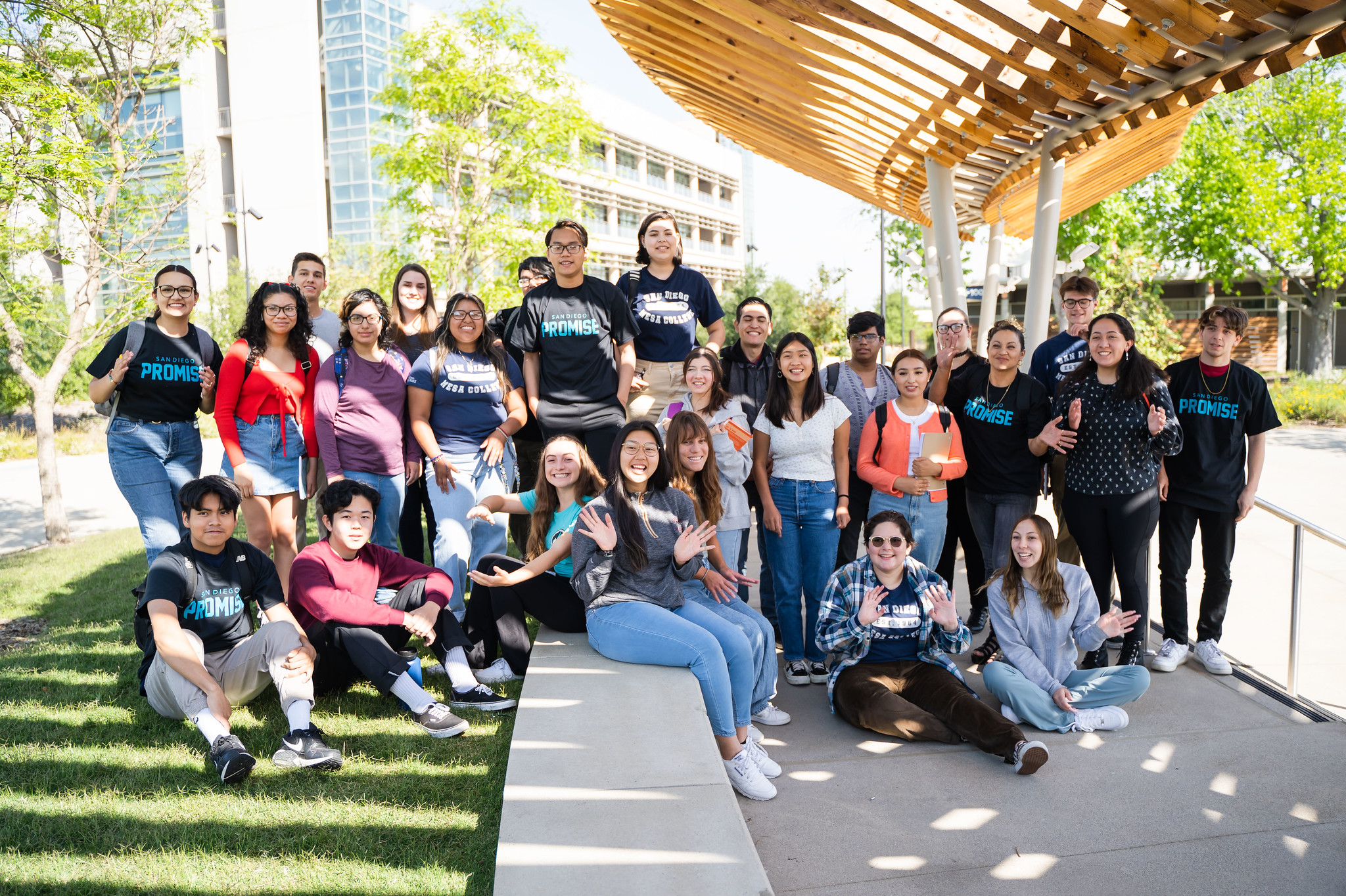 About thirty students outside in the Mesa quad all waving to the camera.